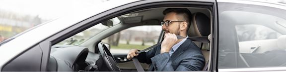 Un homme en costume au volant d'une voiture