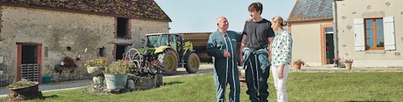 Cerise en compagnie d'une famille d'agriculteurs dans une ferme, devant un tracteur.