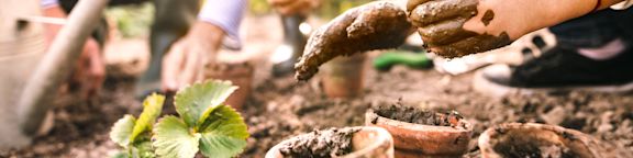 Des enfants jardinent avec de la terre et des pots.