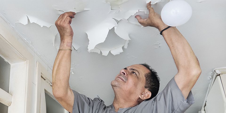 Un homme qui constate un dégât des eaux sur son plafond.