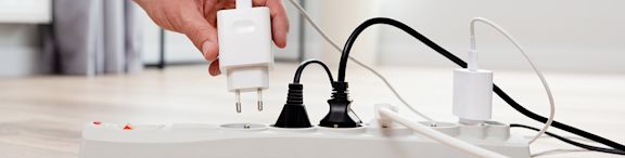 Une personne branche un chargeur sur une multiprise électrique